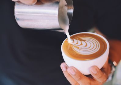 man's hand holding a mug which he pours coffee in